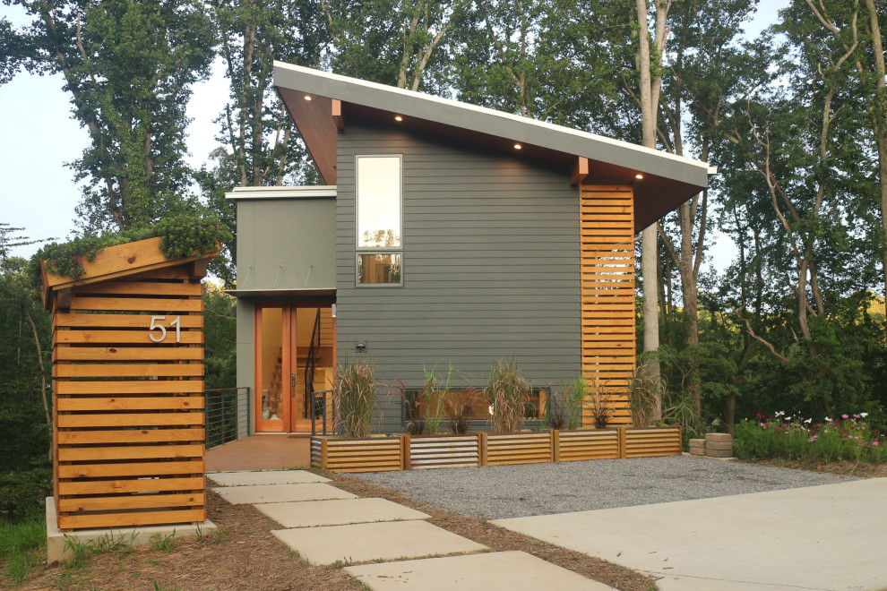 На фото: серый, двухэтажный частный загородный дом среднего размера в современном стиле с облицовкой из цементной штукатурки, односкатной крышей и металлической крышей