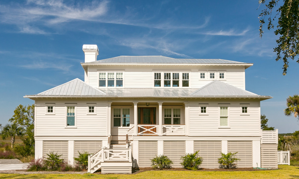 Foto della facciata di una casa piccola bianca stile marinaro a due piani con rivestimento con lastre in cemento e tetto a padiglione