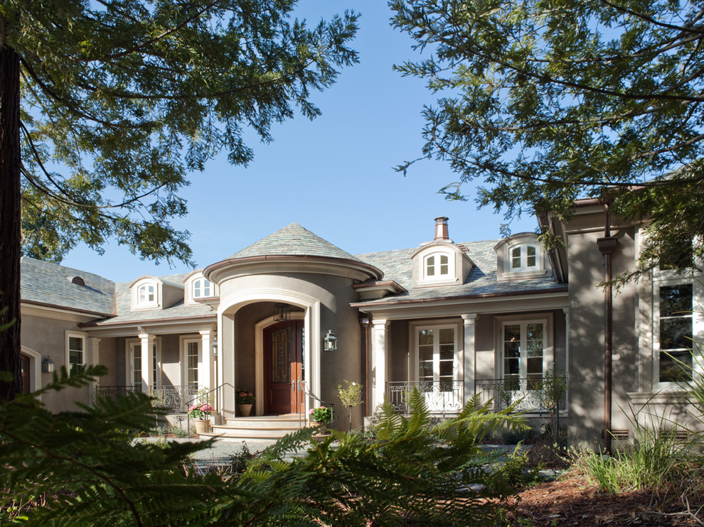 Imagen de fachada de casa beige clásica grande de una planta con revestimiento de estuco y tejado a dos aguas