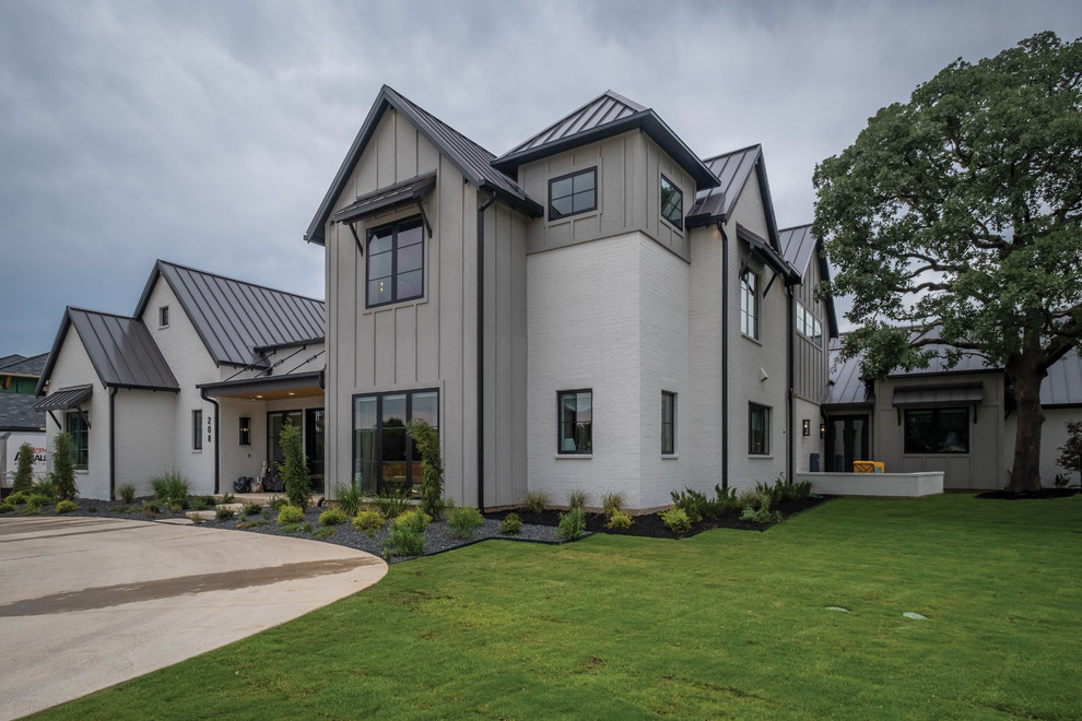 Imagen de fachada de casa gris contemporánea de tamaño medio de dos plantas con revestimientos combinados, tejado a dos aguas y tejado de metal