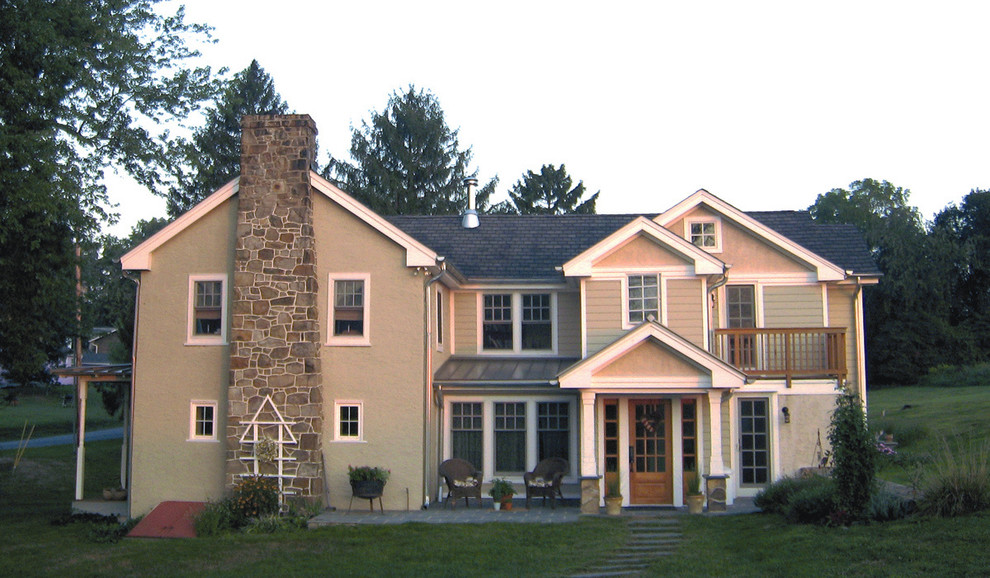 Imagen de fachada beige campestre de tamaño medio de dos plantas con revestimiento de estuco y tejado a dos aguas