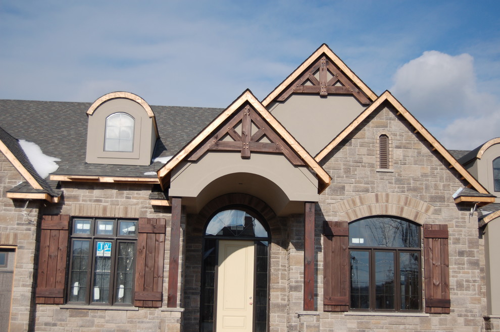 Medium sized and gey traditional two floor house exterior in Toronto with stone cladding and a pitched roof.