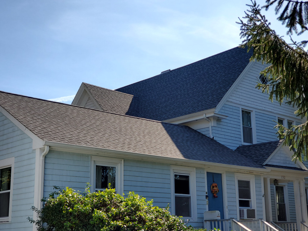 Cette photo montre une façade de maison chic avec un toit en shingle et un toit noir.