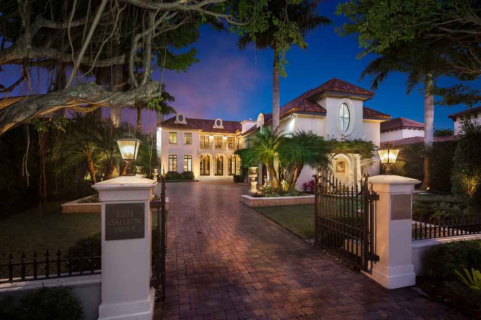 Example of a huge tuscan beige two-story stucco house exterior design in Miami with a tile roof
