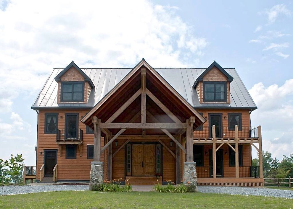Ejemplo de fachada de casa marrón rural grande de tres plantas con revestimiento de madera, tejado a dos aguas y tejado de metal