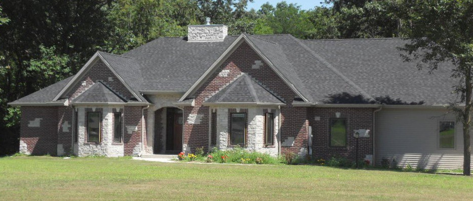 Idée de décoration pour une façade de maison rouge tradition en brique de taille moyenne et de plain-pied avec un toit à quatre pans et un toit en shingle.