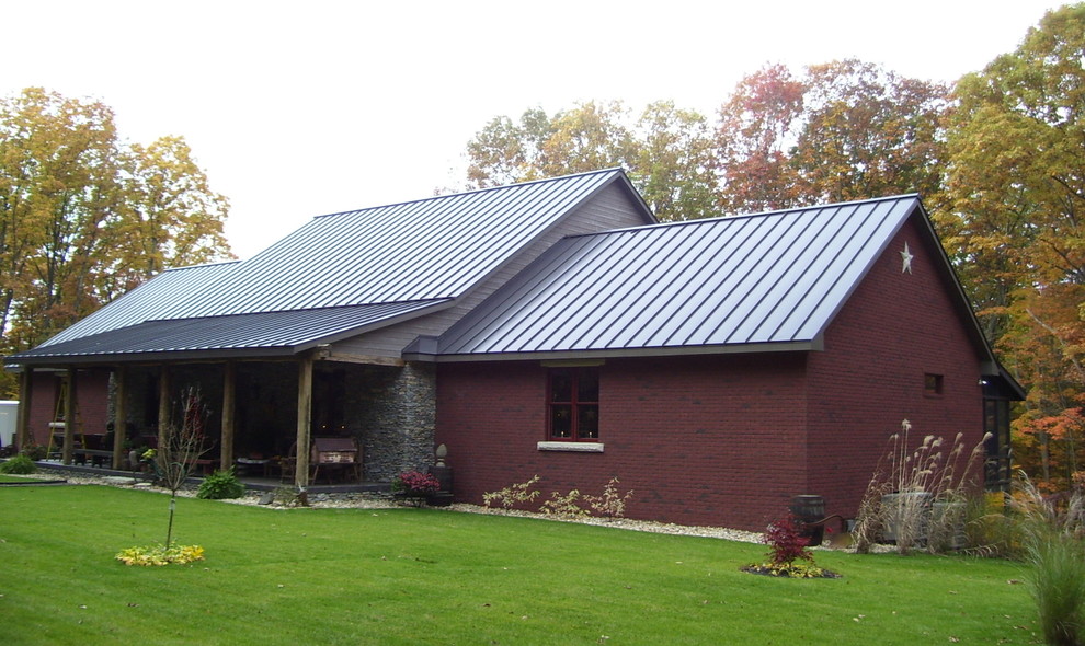 Aménagement d'une façade de maison rouge campagne en brique de taille moyenne et de plain-pied avec un toit à deux pans et un toit en métal.