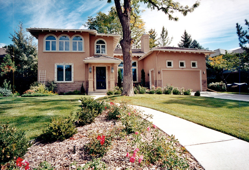 Modelo de fachada de casa beige de estilo americano de tamaño medio de dos plantas con revestimiento de estuco