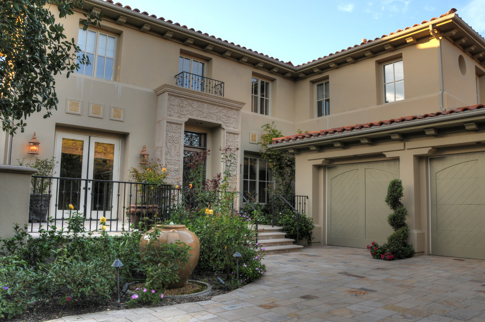 Inspiration for a large mediterranean beige two-story stucco exterior home remodel in Orange County with a tile roof