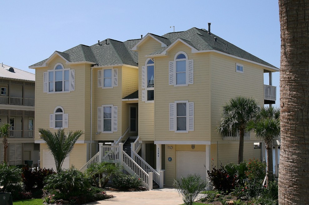 Foto della villa grande gialla stile marinaro a tre piani con rivestimento in legno, tetto a padiglione e copertura a scandole