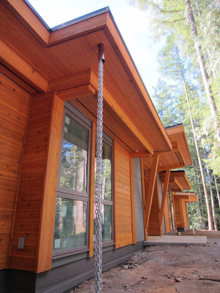 Réalisation d'une très grande façade de maison marron design en bois de plain-pied avec un toit plat et un toit en tuile.