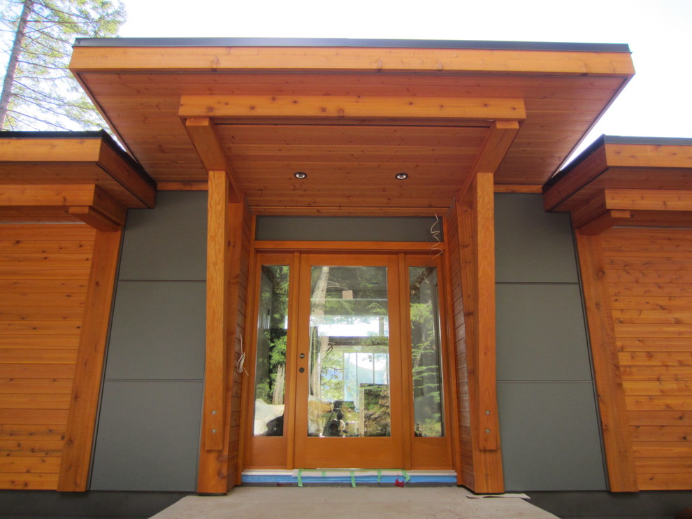 Ejemplo de fachada de casa marrón contemporánea extra grande de una planta con revestimiento de madera, tejado plano y tejado de teja de barro