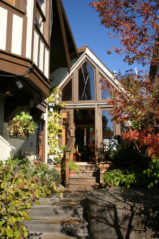 Esempio della facciata di una casa piccola bianca eclettica a due piani con rivestimento in legno e tetto a capanna