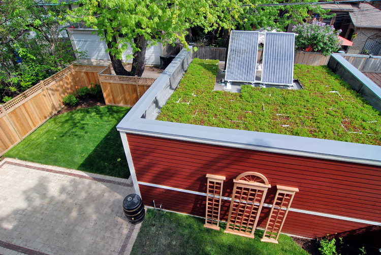 Idées déco pour une façade de maison rouge classique en panneau de béton fibré avec un toit végétal.