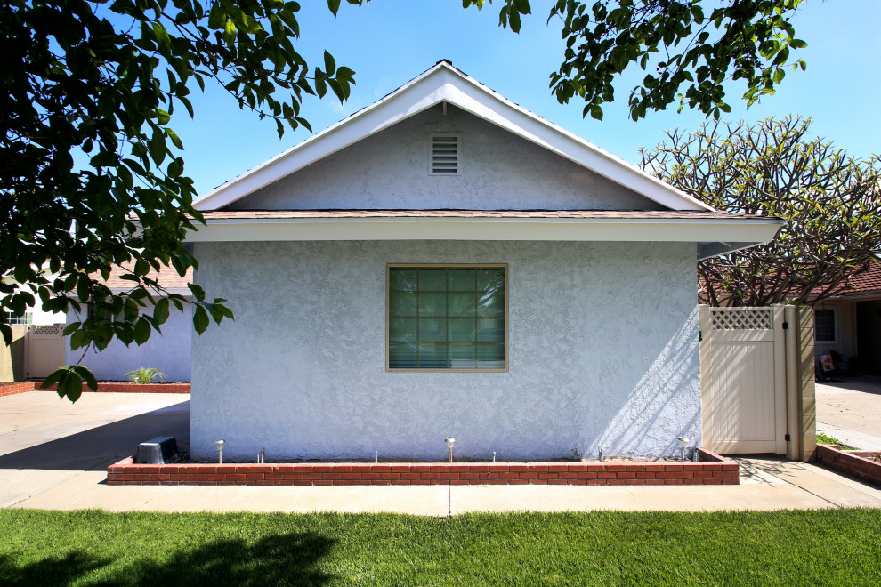 Diseño de fachada de casa azul de estilo americano de tamaño medio de una planta con revestimiento de estuco, tejado a dos aguas y tejado de teja de madera