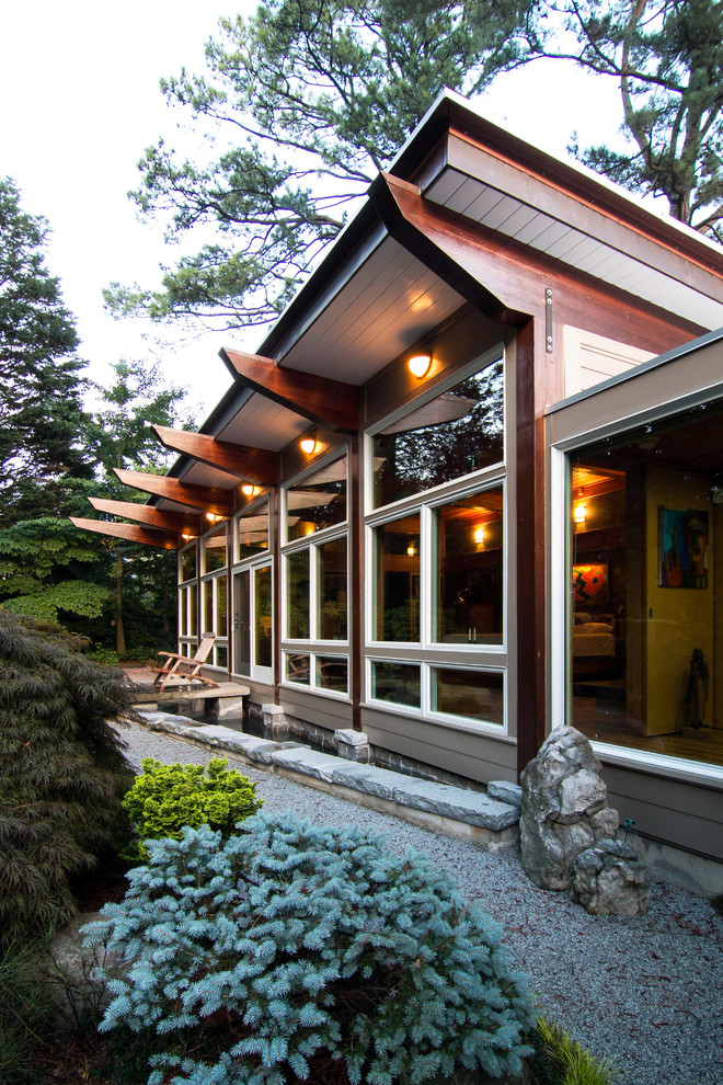 На фото: одноэтажный, большой, серый частный загородный дом в японском стиле в восточном стиле с облицовкой из ЦСП и односкатной крышей