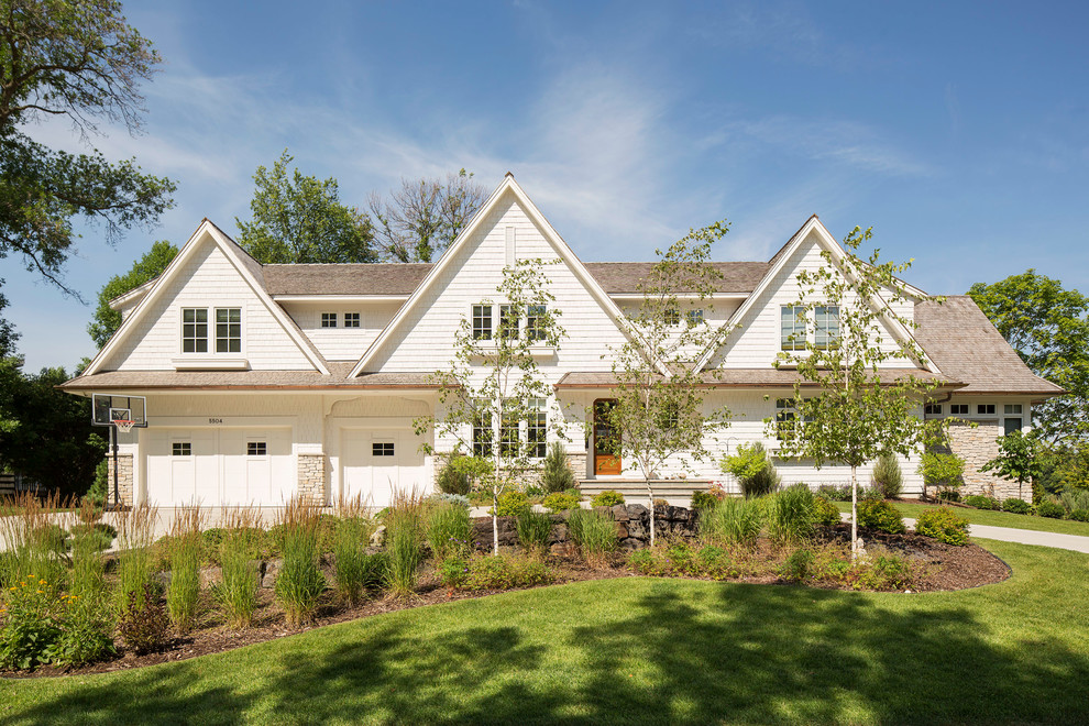 This is an example of a large and white classic house exterior in Minneapolis with a pitched roof and wood cladding.
