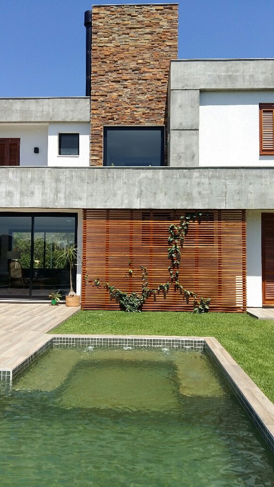 Esempio della facciata di una casa contemporanea a piani sfalsati con rivestimenti misti e tetto piano