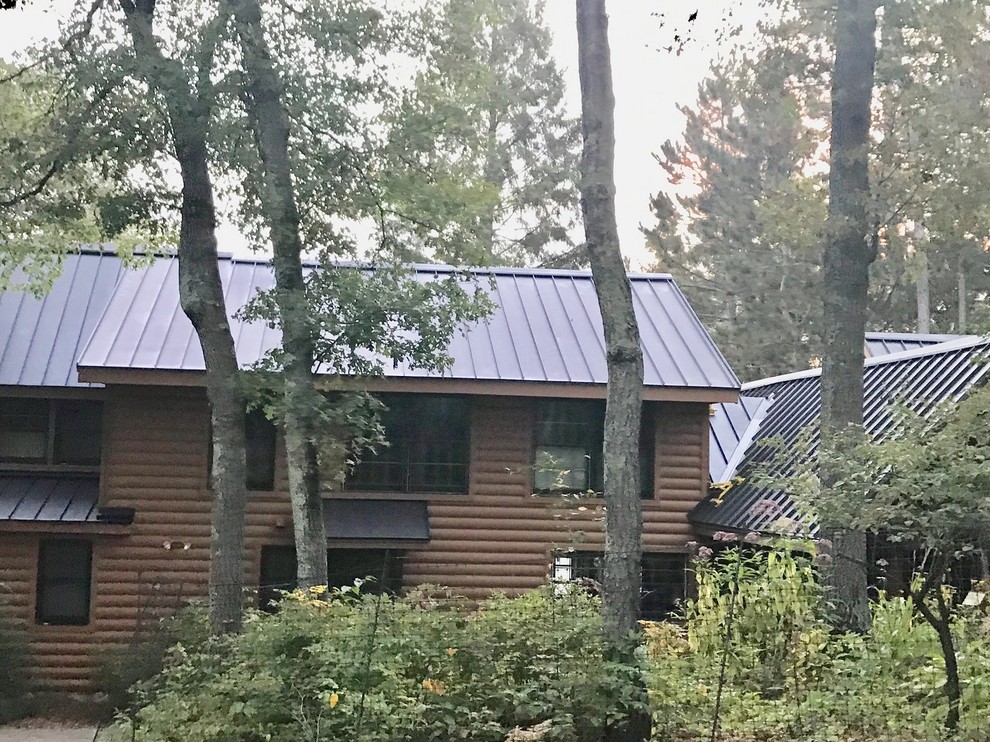 Ejemplo de fachada de casa marrón rural extra grande de una planta con tejado de metal