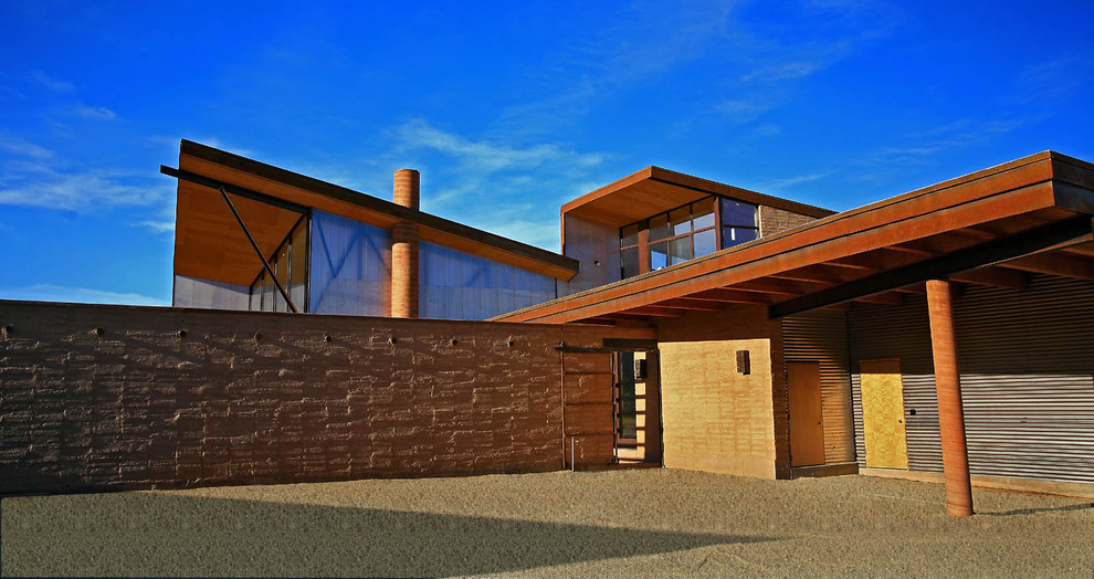 Пример оригинального дизайна: большой, двухэтажный, коричневый дом в стиле модернизм с облицовкой из металла и односкатной крышей