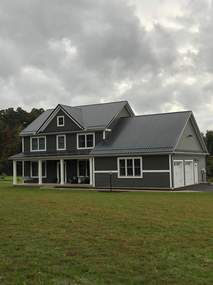 Exemple d'une façade de maison marron nature de taille moyenne et à un étage avec un revêtement en vinyle, un toit à deux pans et un toit en métal.