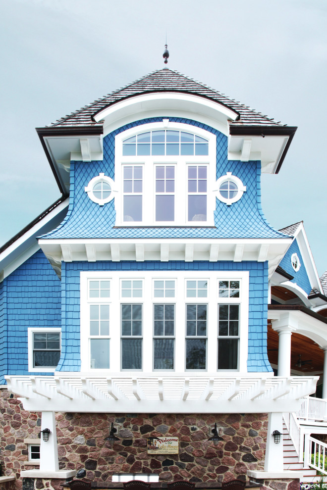 Imagen de fachada de casa azul marinera grande de tres plantas con revestimientos combinados