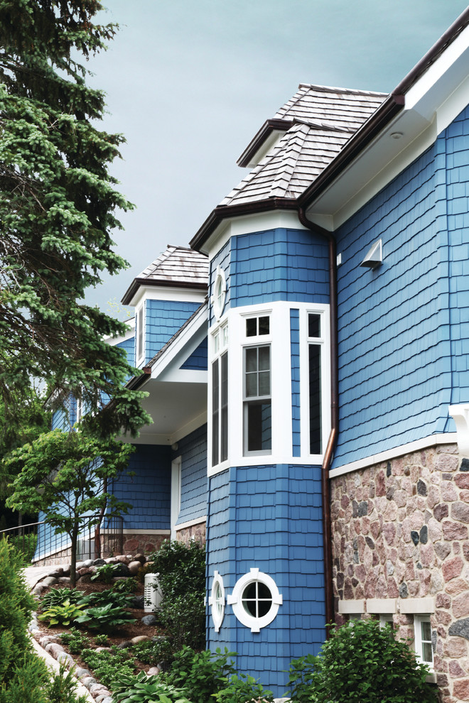 Modelo de fachada de casa azul costera grande de tres plantas con revestimientos combinados