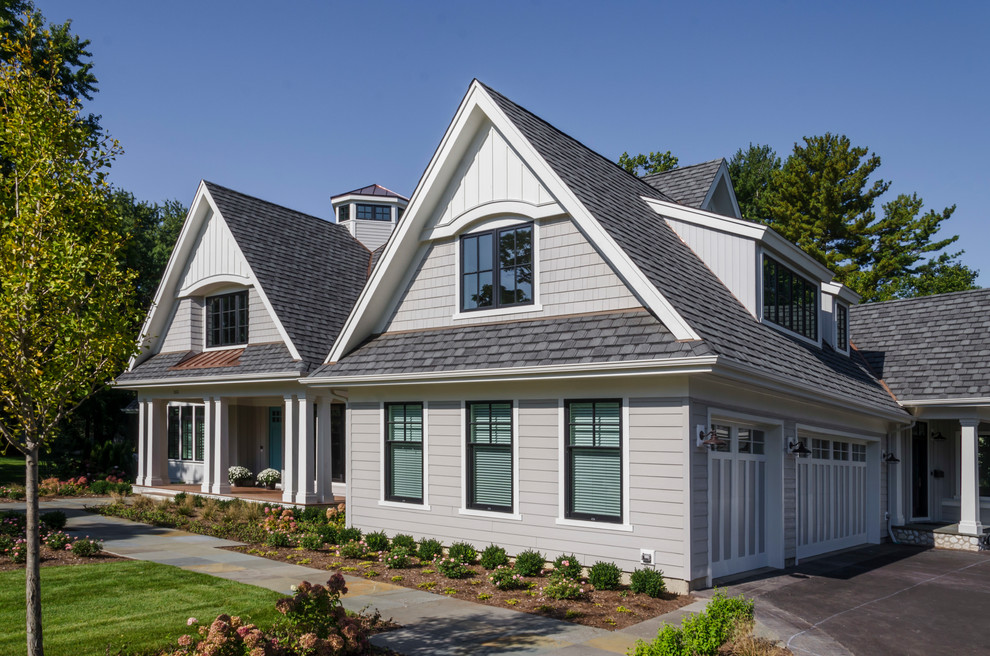 Cette image montre une grande façade de maison grise traditionnelle à un étage avec un revêtement mixte, un toit à croupette et un toit mixte.