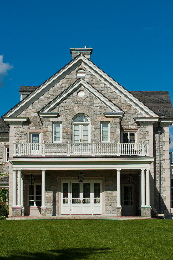 Large traditional three-story stone gable roof idea in New York