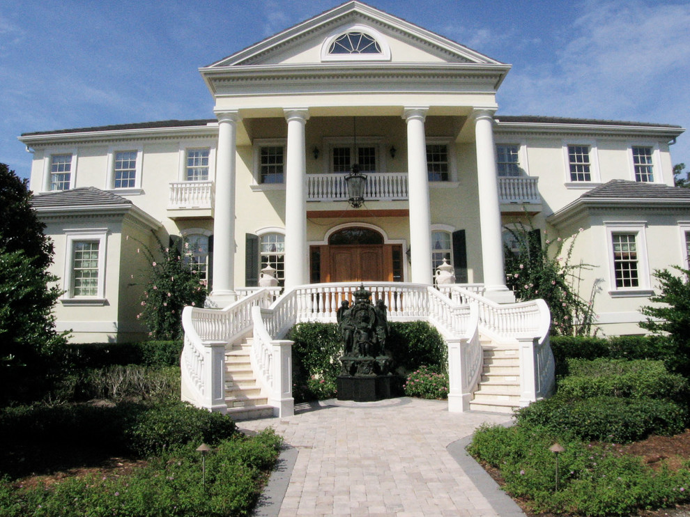 Immagine della facciata di una casa grande classica a due piani con rivestimento in stucco