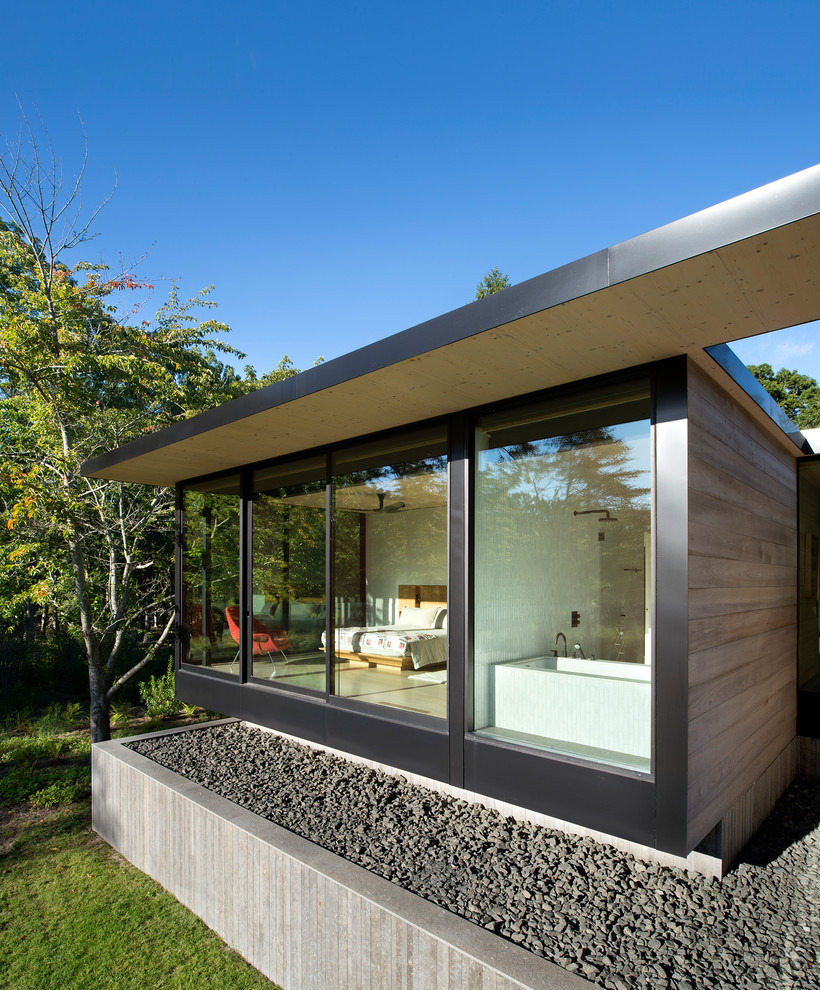 Imagen de fachada de casa de tamaño medio de una planta con revestimiento de madera y tejado plano