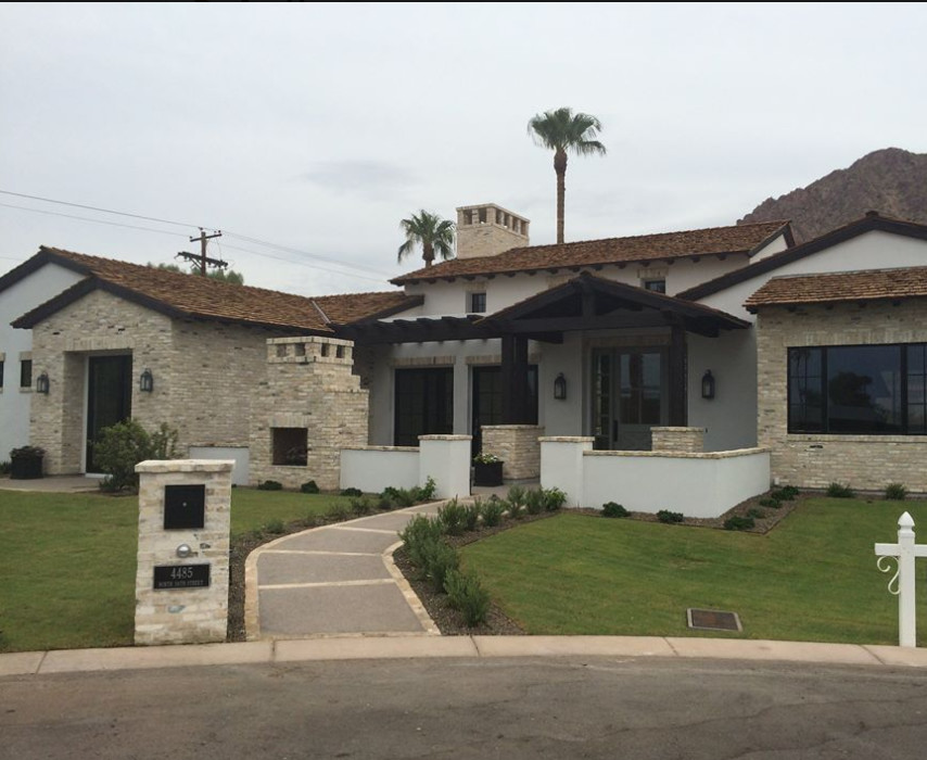 Inspiration for a large southwestern white two-story stone gable roof remodel in Phoenix