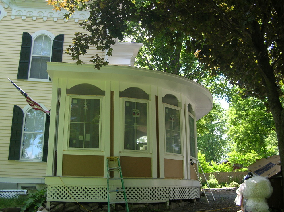 Photo of a large and yellow victorian house exterior in Boston with three floors, wood cladding and a pitched roof.