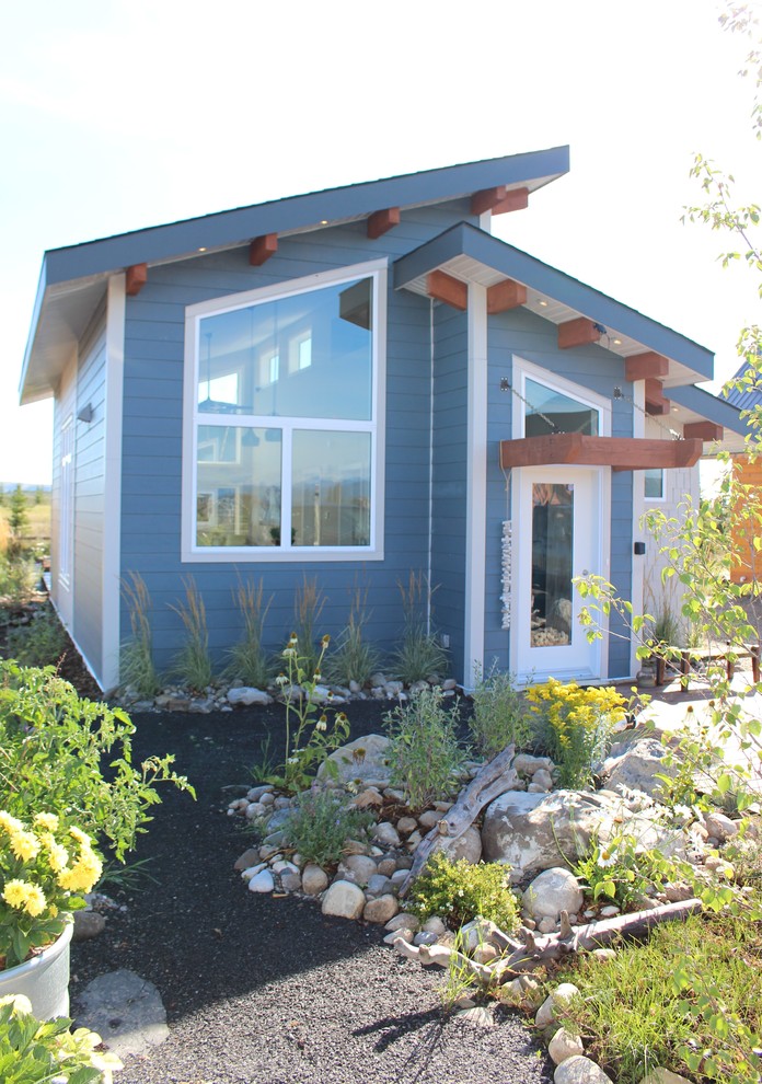 Modelo de fachada de casa azul costera pequeña de una planta con revestimiento de aglomerado de cemento y tejado a dos aguas