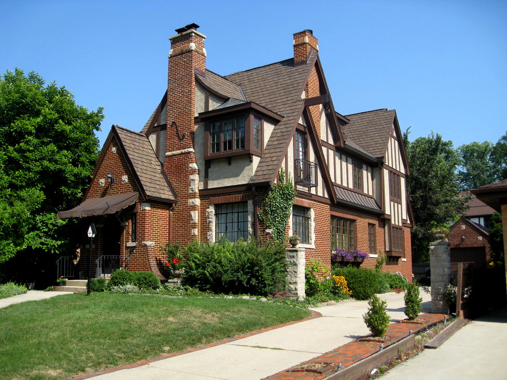 Ejemplo de fachada de casa roja y marrón tradicional grande de tres plantas con revestimientos combinados, tejado a dos aguas y tejado de teja de madera