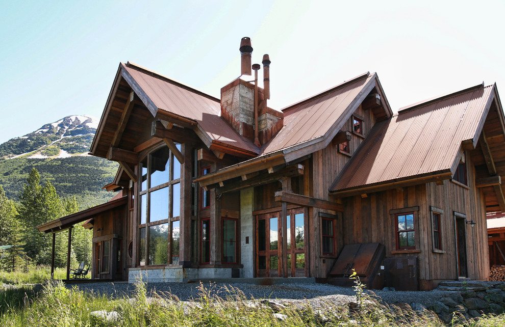 Inspiration pour une grande façade de maison marron chalet en bois à un étage avec un toit à deux pans et un toit en métal.