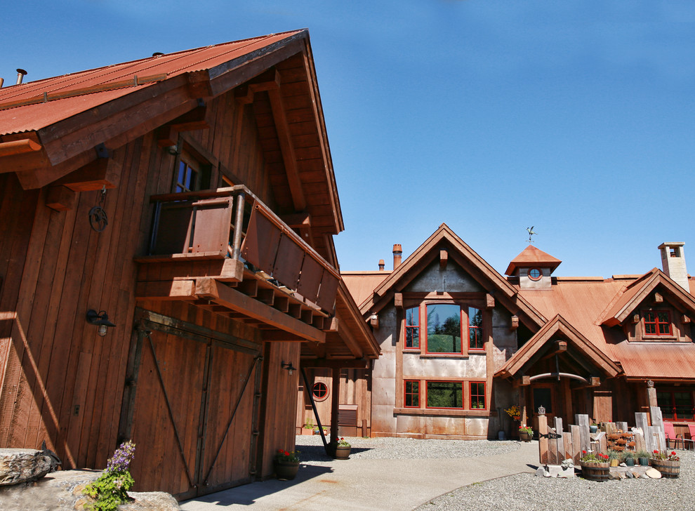 Imagen de fachada de casa marrón rústica grande de dos plantas con revestimiento de madera, tejado a dos aguas y tejado de metal