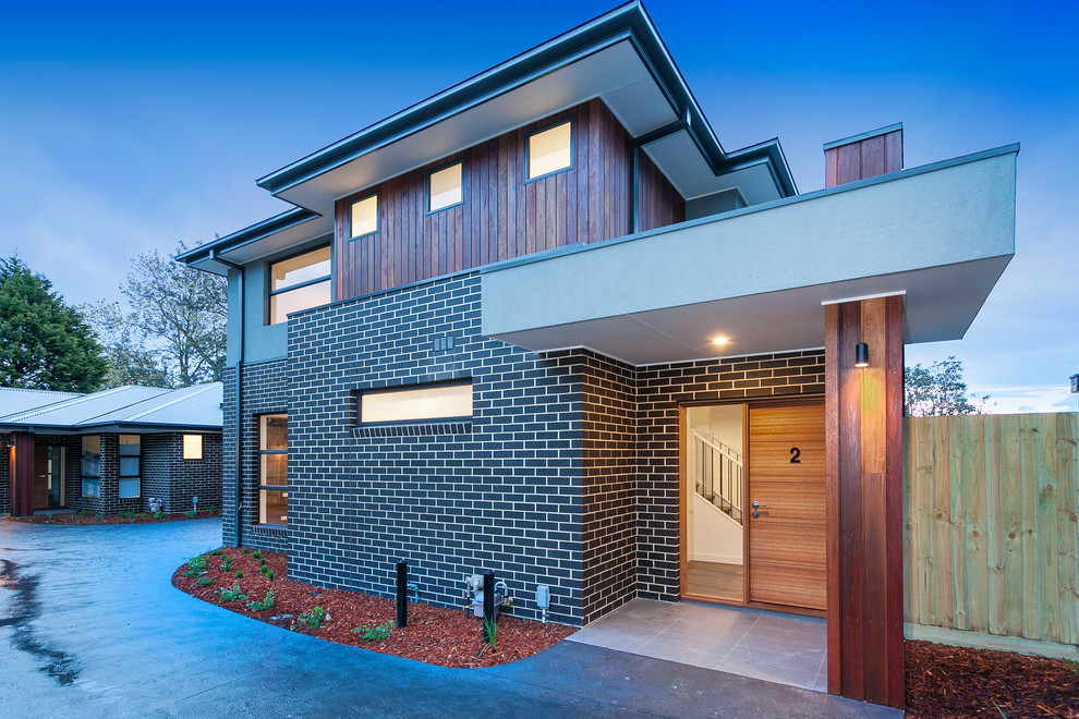 Mittelgroßes, Zweistöckiges Modernes Reihenhaus mit Mix-Fassade, schwarzer Fassadenfarbe, Walmdach und Blechdach in Melbourne
