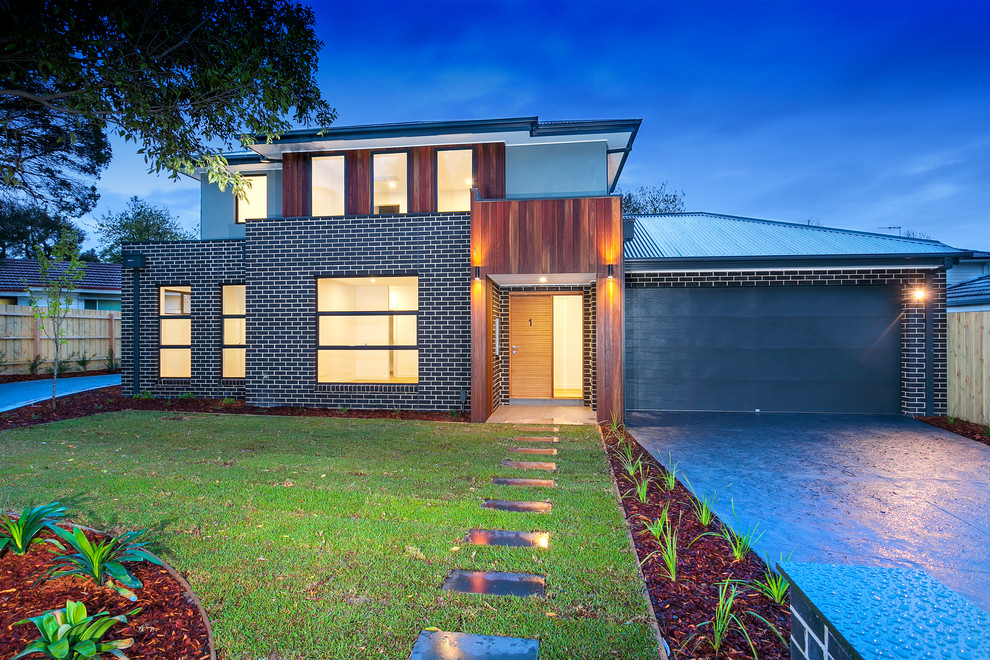 Mittelgroßes, Zweistöckiges Modernes Reihenhaus mit Mix-Fassade, schwarzer Fassadenfarbe, Walmdach, Blechdach und schwarzem Dach in Melbourne