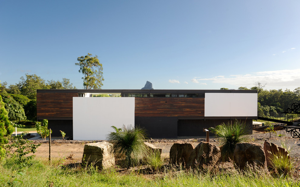 На фото: двухэтажный, коричневый дом среднего размера в стиле модернизм с комбинированной облицовкой и плоской крышей с