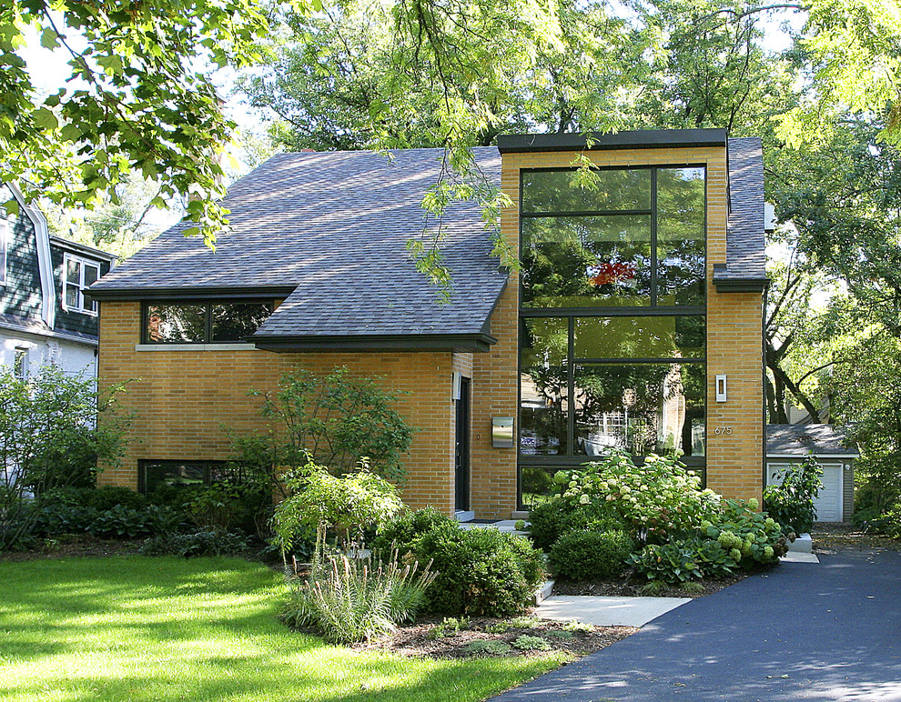 Immagine della facciata di una casa grande gialla contemporanea a due piani con rivestimento in mattoni e tetto a capanna