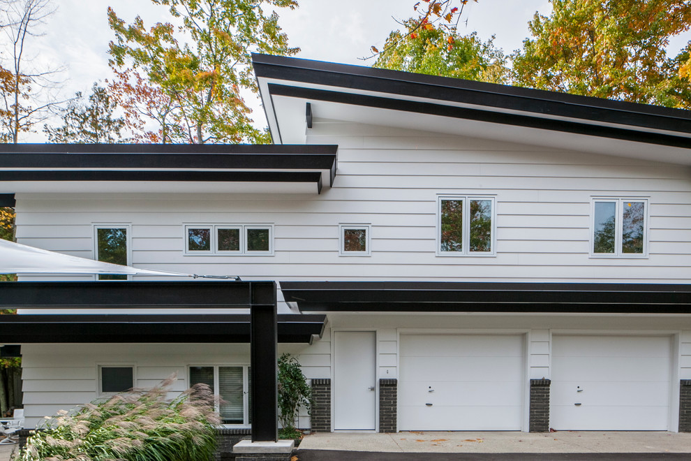 Ejemplo de fachada blanca vintage grande a niveles con revestimientos combinados y tejado plano