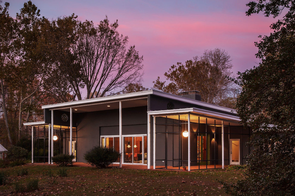 На фото: большой, одноэтажный, серый дом в стиле ретро с облицовкой из цементной штукатурки и односкатной крышей с