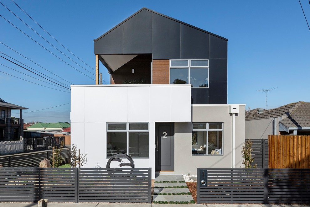 Idées déco pour une façade de maison multicolore contemporaine en stuc à un étage avec un toit à deux pans.