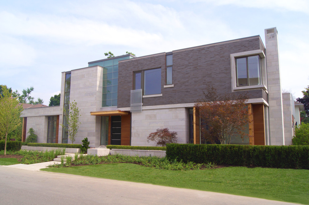 Foto della facciata di una casa grande grigia contemporanea a due piani con rivestimento in mattoni e tetto piano