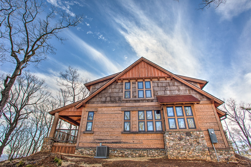 На фото: огромный, двухэтажный, деревянный, коричневый дом в стиле рустика с двускатной крышей с
