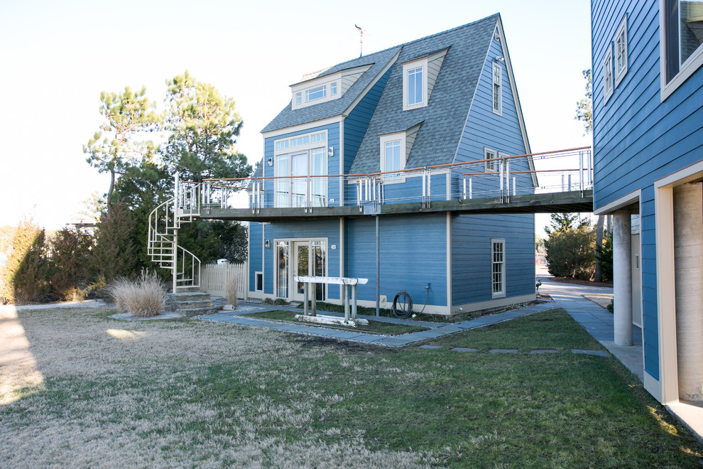 Large and blue modern house exterior in Other with three floors, wood cladding and a pitched roof.