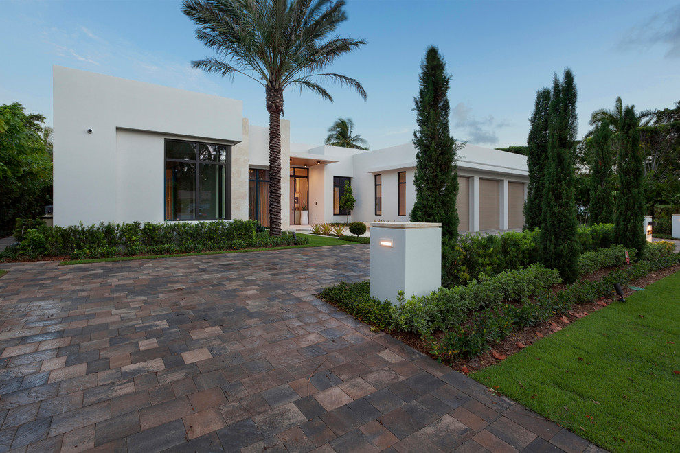 This is an example of an expansive and white contemporary bungalow render house exterior in Miami with a flat roof.