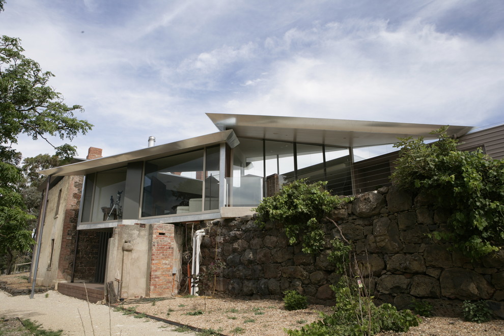 Cette image montre une façade de maison grise design en bois à un étage.