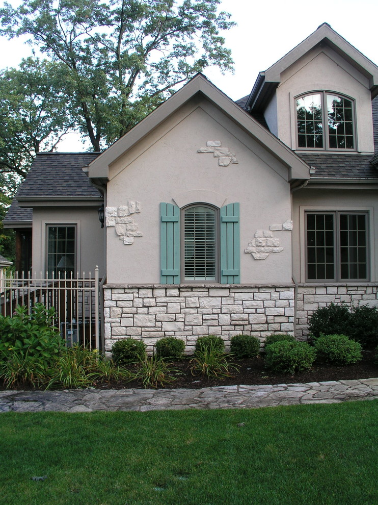 Modelo de fachada beige clásica de dos plantas con revestimiento de estuco y tejado a cuatro aguas